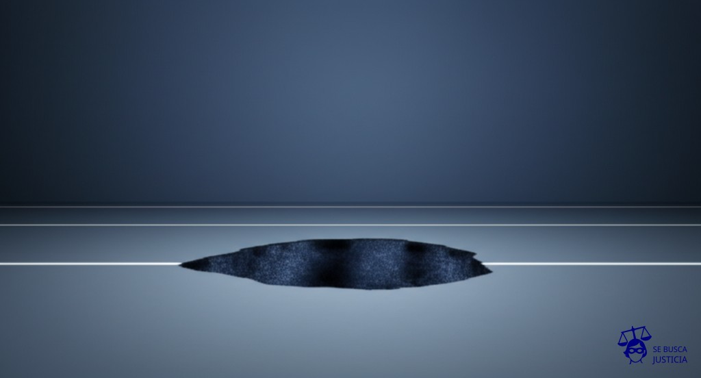 Un gran agujero en el suelo con forma de boca abierta, justo en medio de un camino liso. Representa: Accidente en obra vial sin desvío señalizado