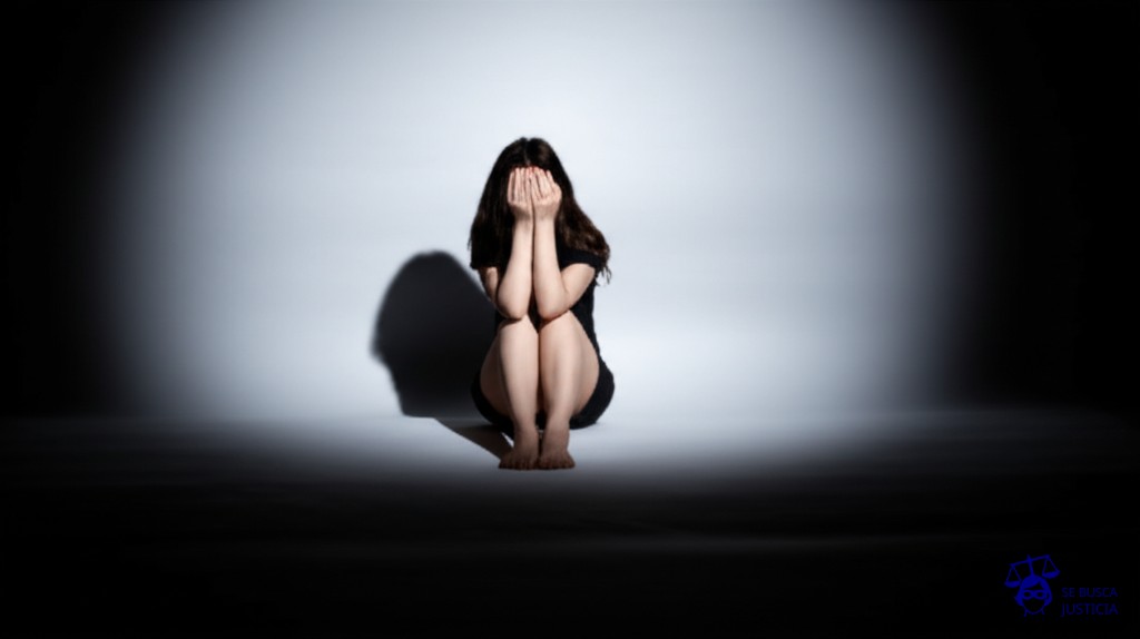 Un gran foco de luz apuntando directamente a una pequeña y solitaria figura, que se encoge y se cubre el rostro con las manos. Representa: Actos administrativos que afectan el honor o la intimidad