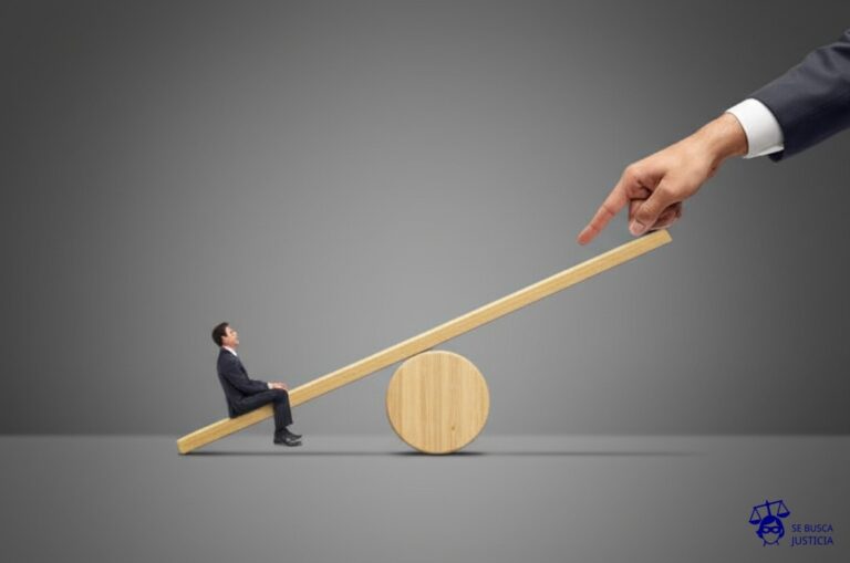Un balancín con dos lados idénticos, pero uno está ligeramente más alto que el otro. Un hombrecillo está sentado en el lado más bajo, y alguien invisible empuja el balancín para que se incline aún más, haciéndolo caer. Representa: Despido por ideología política