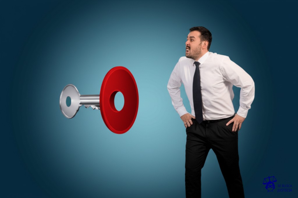 Un hombre intentando meter una enorme y pesada llave cuadrada en una cerradura redonda, con un gesto de frustración evidente. Representa: Dificultad para acceder a créditos hipotecarios por requisitos abusivos