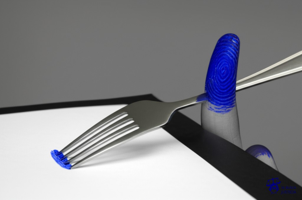 Un dedo manchado de tinta intentando firmar un documento con un tenedor. Representa: Falsificación de firma en autorización de viaje del menor