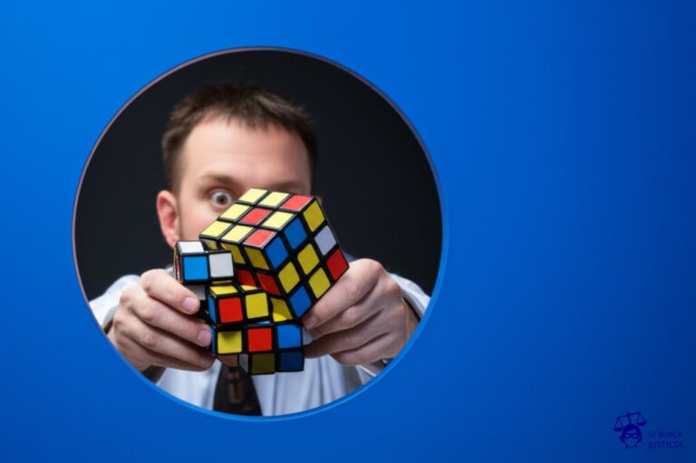 Un hombre intentando encajar un cubo de Rubik desarmado, con las piezas revueltas y de diferentes tamaños, dentro de un agujero con forma de círculo. Representa: Falta de criterios claros para el ajuste por inflación impositivo