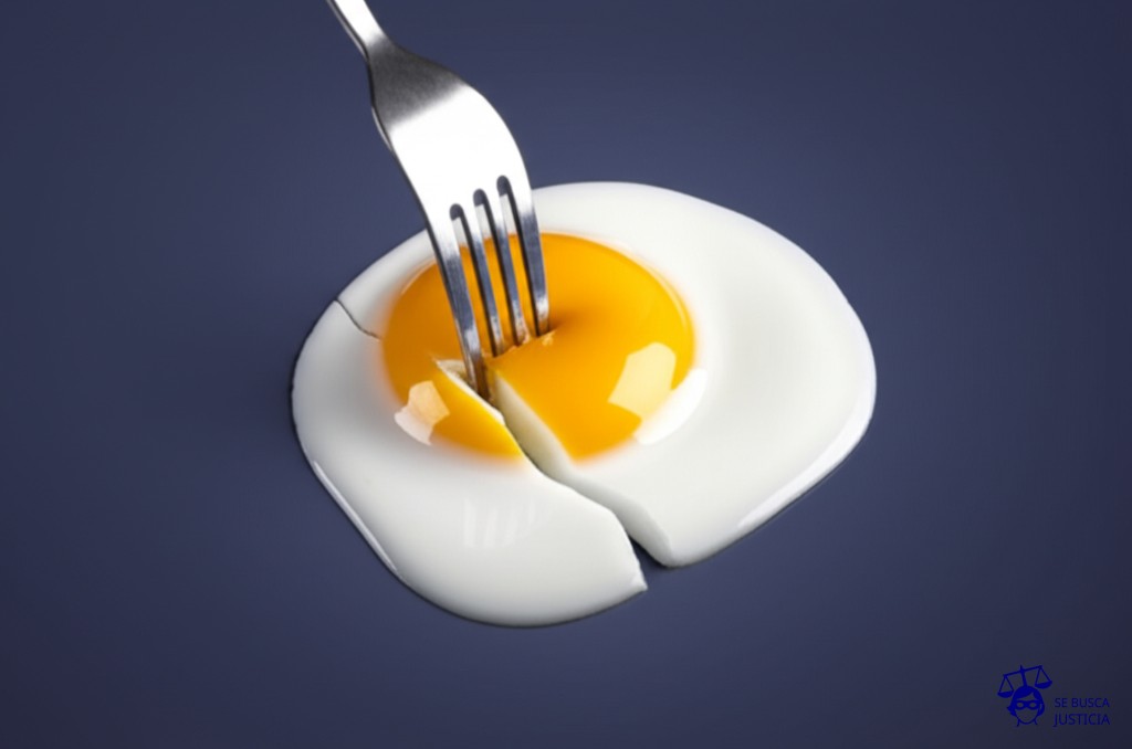 Un huevo frito con una gran grieta en la yema, y un tenedor a punto de pincharlo. Representa: Impugnación de paternidad tras separación
