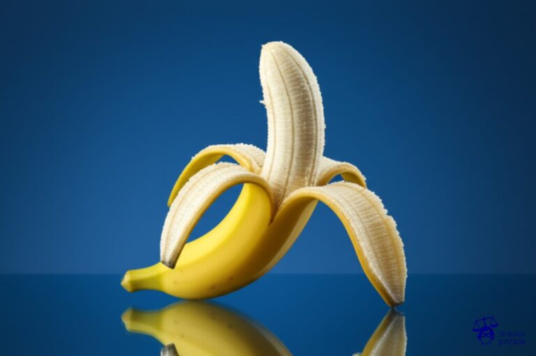 Un plátano, con la cáscara medio despegada, sobre una superficie lisa y brillante. Representa: Lesión por resbalón en piso mojado no señalizado