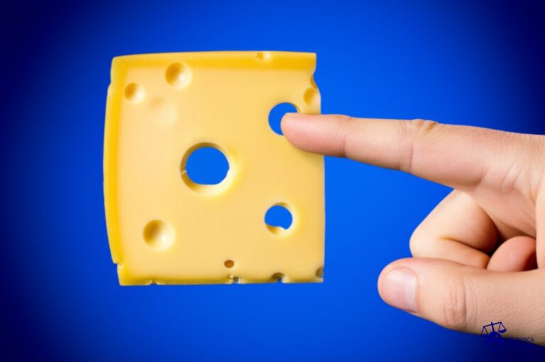 Un gran queso suizo con un agujero perfectamente circular, y un dedo apuntando descaradamente a ese agujero. Representa: Penalti polémico en la final de la FA Cup 2005 (Arsenal vs Manchester United)